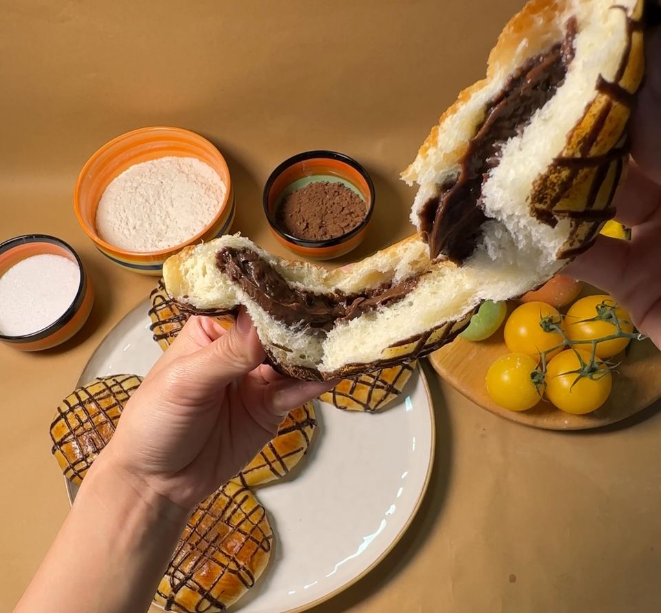 A chocolate bun torn open, filled with chocolate