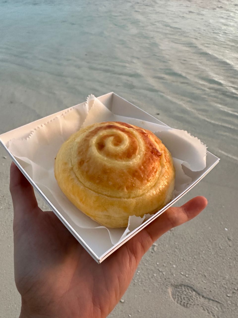 A cream bun held over the sea