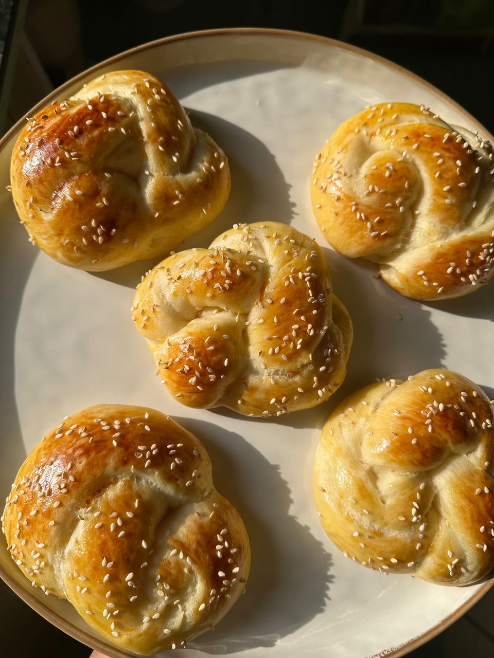 Sesame knot buns on a plate in the sun