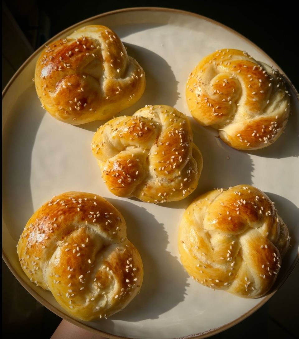 Five sesame knot buns on a cream plate