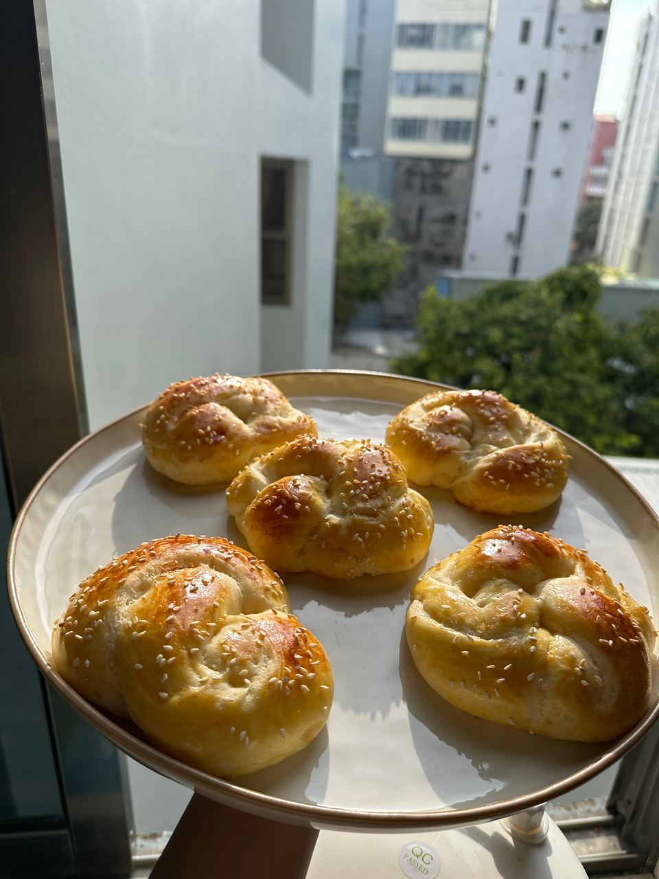 A plate of sesame knot buns by a sunny window